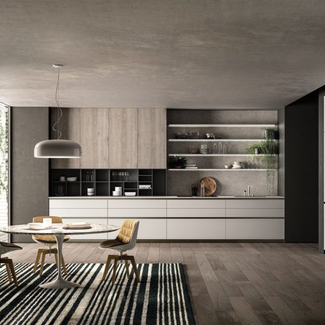 medium-E0_GENERALE Cucina moderna senza maniglia E0 con pensili bianchi, grigi e color legno e al centro della stanza un tavolo rotondo a tre posti.