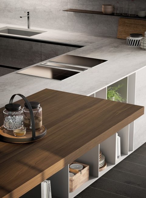medium-E0_LAMINAM_PARTICOLARE-1 Dettaglio del piano di lavoro della cucina moderna con gola E0, con piano in cemento chiaro, e tavolo integrato in legno.